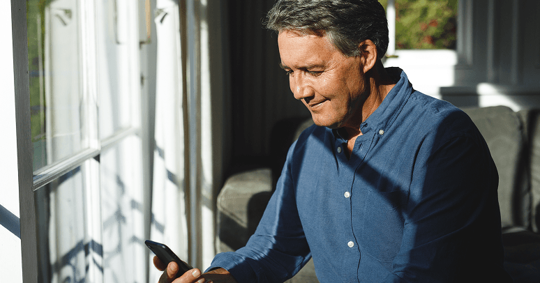 Man looking at his phone close to window